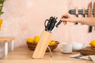 Kadın ve bıçaklar mutfakta masanın üzerinde duruyor.