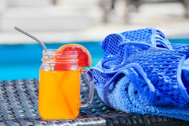 Mason kavanozu, havluyla, havluyla ve mayosuyla yüzme havuzunun yanında, yakın plan.