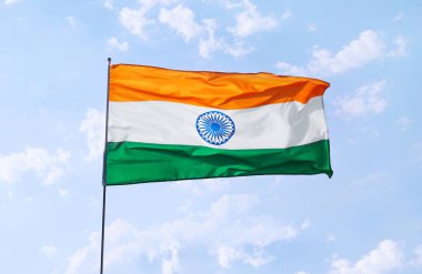 Mavi gökyüzü arka planında Hindistan bayrağı sallıyor