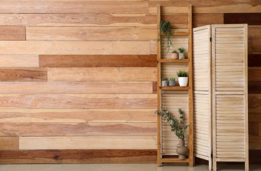 Ev bitkileri ve ahşap duvarın yanındaki katlı perdeli merdiven.