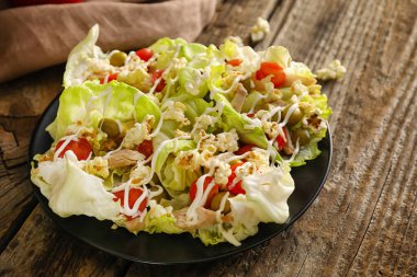 Tahta arka planda marullu lezzetli patlamış mısır salatası.