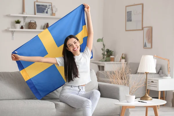 家里挂着瑞典国旗的年轻女子 — 图库照片