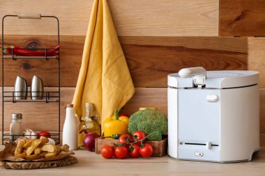 Modern fritöz ve ürünler ahşap duvarın yanındaki masada.