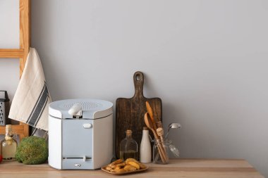 Modern fritöz ve lezzetli patates ışık duvarının yanındaki masada.