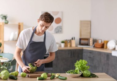 Genç adam mutfakta brokoli kesiyor.