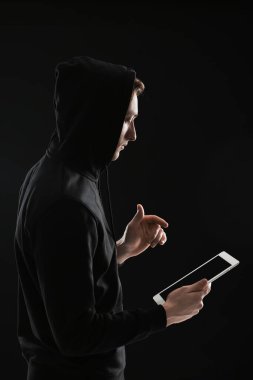 Koyu arkaplanda tablet bilgisayarı olan hacker silueti