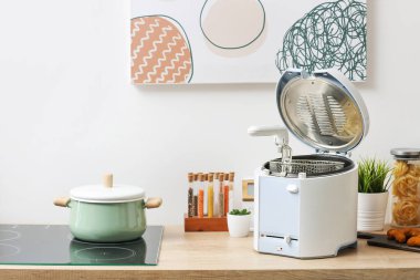 Mutfaktaki masada tencere ve modern fritöz.