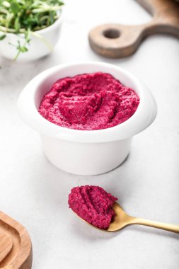 Hafif arka planda pancar humusu olan bir kase ve kaşık.