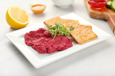 Lezzetli pancar humuslu tabak ve arka planda krakerler.