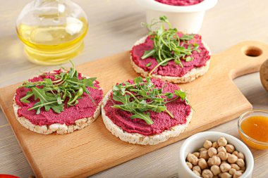 Lezzetli pancar humuslu pirinç krakerleri ve gri ahşap arka planda taze lahanalar.