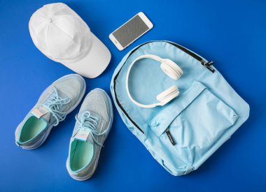 Spor ayakkabıları, sırt çantası, şapka, cep telefonu ve kulaklık.