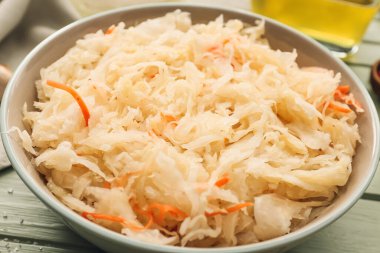 Lezzetli lahana turşusu ve ahşap arka planda malzemelerle dolu bir kase.