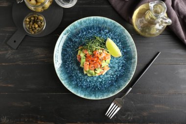 Koyu ahşap arka planda lezzetli somon tartartarı.