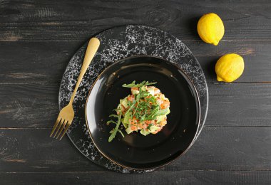 Koyu ahşap arka planda lezzetli somon tartartarı.