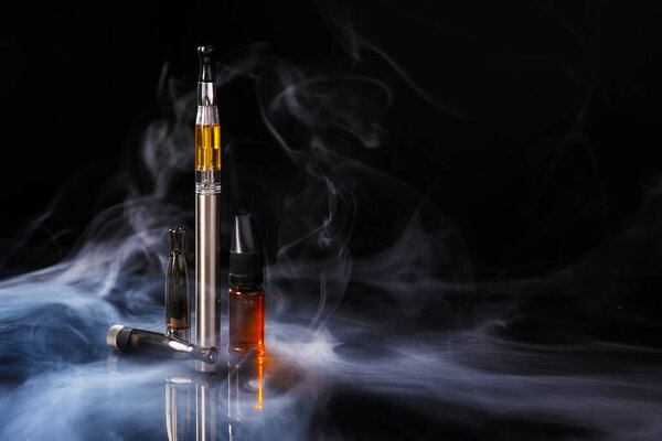 Electronic cigarette with oil on dark background with fume
