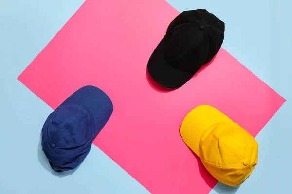 Stylish baseball hats on color background