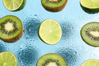 Su damlalarıyla renklendirilmiş limon ve kivi dilimleri, yakın plan.