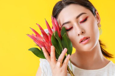 Arka planda protea çiçeği olan güzel genç bir kadın.