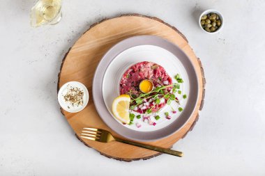 Lezzetli tartarlı et tabağı ve açık arkaplanda sos.