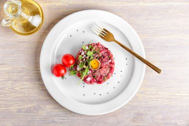 Hafif ahşap arka planda lezzetli etli tartar tabağı.