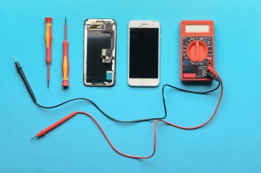 Renk arkaplan üzerinde teknisyen araçları olan parçalanmış cep telefonu