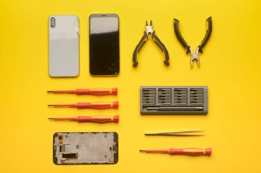 Arkaplanda teknisyen araçları olan hasarlı cep telefonları