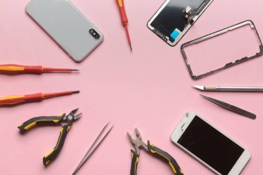 Renk arkaplan üzerinde teknisyen araçları olan hasarlı cep telefonlarından yapılmış çerçeve