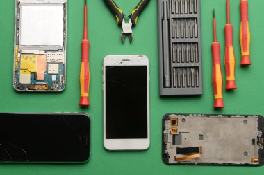 Arkaplanda teknisyen araçları olan hasarlı cep telefonları