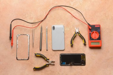 Renk arkaplan üzerinde teknisyen araçları olan parçalanmış cep telefonu