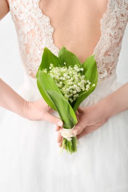 Gelin, açık arkaplanda güzel çiçekleri olan bir buket çiçekle