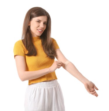 Beyaz arka planda tıbbî yamayı kaldıran genç kadın.