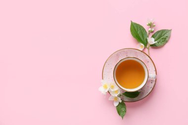 Bir fincan yasemin çayı ve çiçeklerle renklendirilmiş arka plan