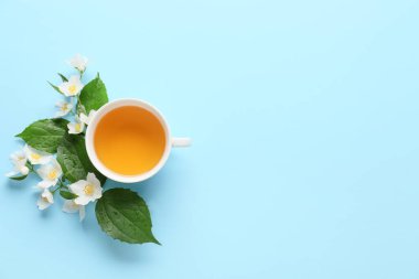 Bir fincan yasemin çayı ve çiçeklerle renklendirilmiş arka plan