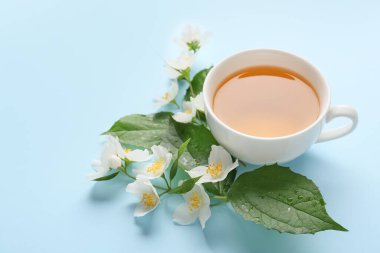 Bir fincan yasemin çayı ve çiçeklerle renklendirilmiş arka plan