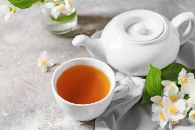 Bir fincan yasemin çayı ve arkaplanda çiçekler ile kompozisyon