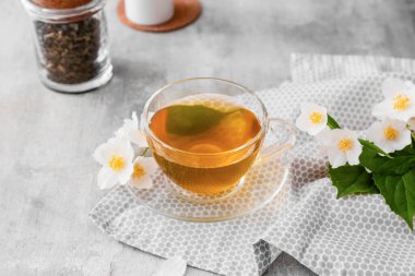 Bir fincan yasemin çayı ve arkaplanda çiçekler.