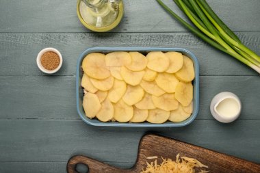 Lezzetli patates güvecini renkli ahşap arka planda pişirme kabında hazırlıyorum.