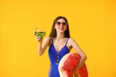 Renkli yüzme yüzüğüyle kokteyl içen güzel bir kadın.