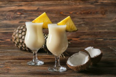 Ahşap zemin üzerinde lezzetli Pina Colada kokteyli olan bardaklar