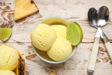 Lezzetli ananaslı kaseler ve hafif ahşap arka planda limon, yakın plan.