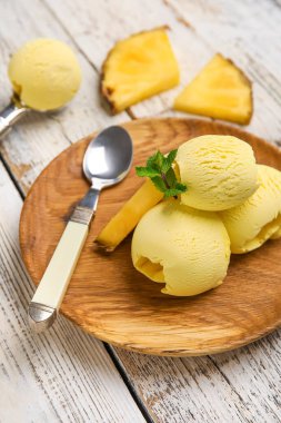 Hafif ahşap arka planda lezzetli ananaslı dondurma tabağı, yakın plan.