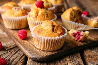 Ahşap arka planda lezzetli ahududu kekleri olan tahta, yakın plan.
