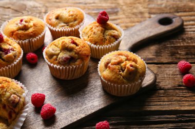 Ahşap arka planda lezzetli ahududu kekleri olan tahta, yakın plan.