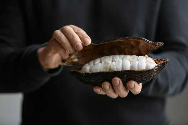 Man holding fresh cocoa fruit, closeup