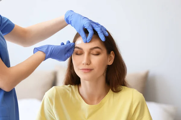 Nurse Applying Medical Patch Young Woman Forehead Clinic — Stock Photo, Image