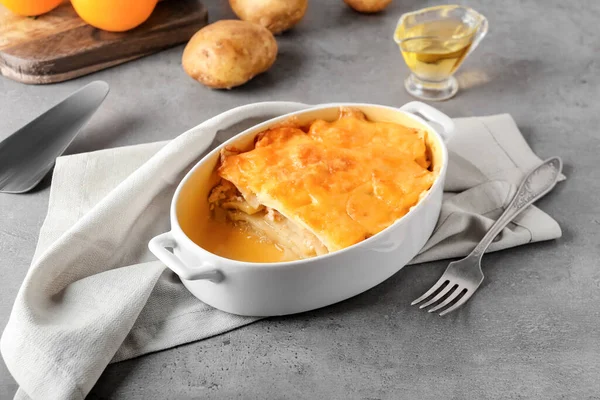 Gri arka planda lezzetli patates güveci olan fırın yemeği.
