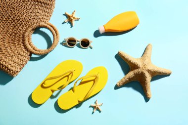 Renk arkaplanında parmak arası terlik, çanta, güneş gözlüğü ve güneş kremi olan kompozisyon