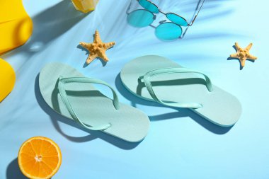 Renkli arka planda şık parmak arası terlikler ve güneş gözlüğü