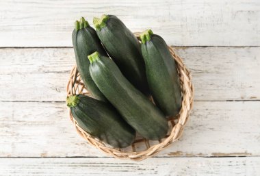 Hafif ahşap zemin üzerinde taze kabak kabakları olan sepet.