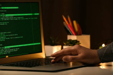 Gece ofiste dizüstü bilgisayarla çalışan kadın programcı.